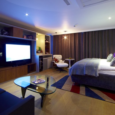 An elegantly furnished hotel room featuring a comfortable bed and a modern television.