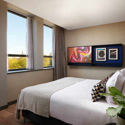 A hotel room featuring a generously-sized bed adorned with an elegant leather headboard.