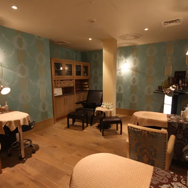 A well-furnished spa treatment room featuring a table, chairs, and a mirror.