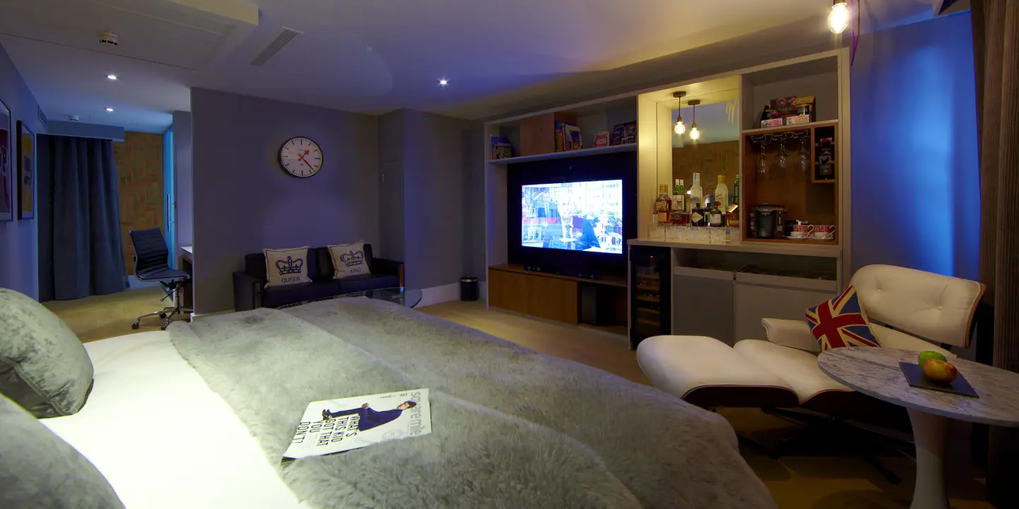 An elegantly furnished bedroom featuring a comfortable bed, a stylish chair, and a modern television.