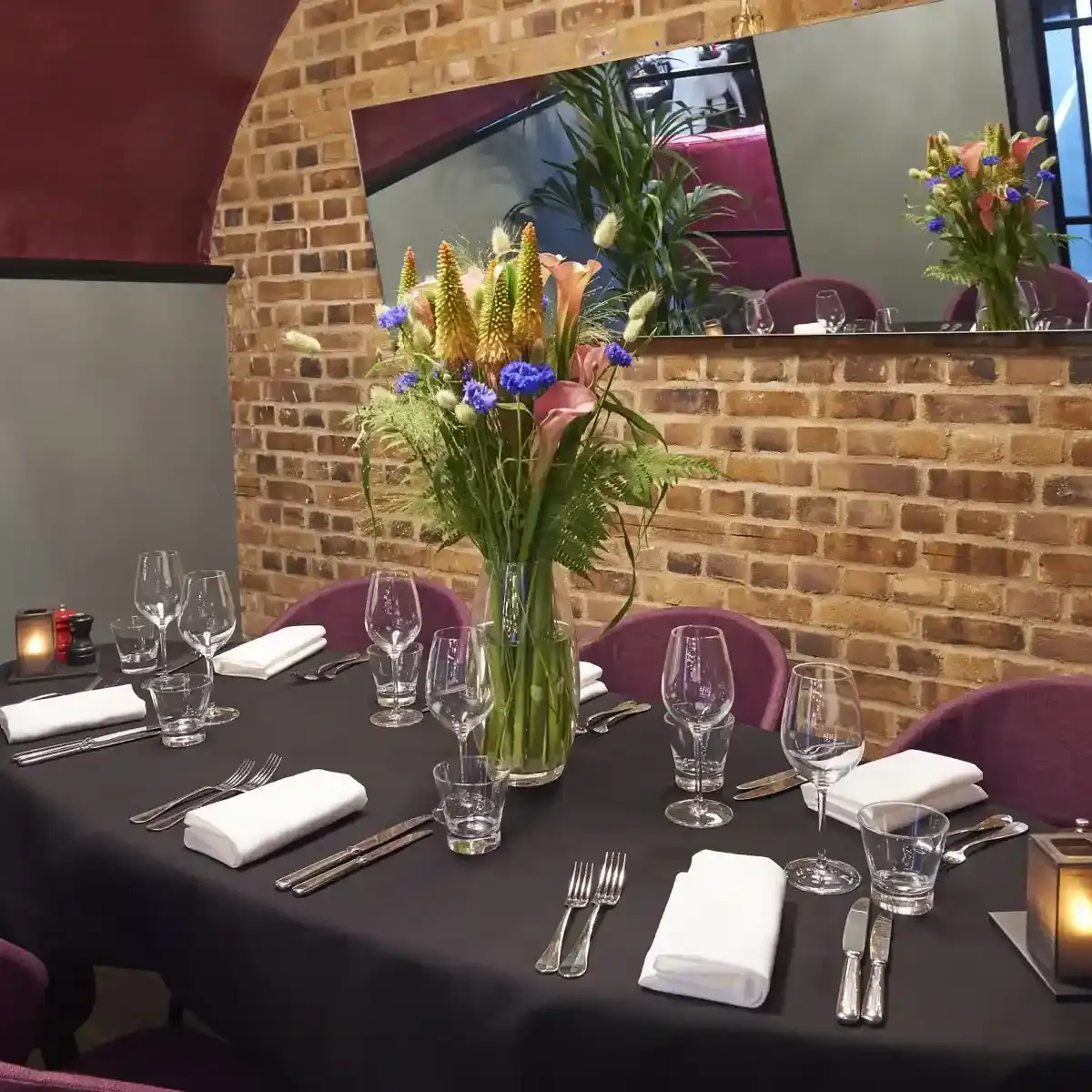 Table with purple chairs against a brick wall.