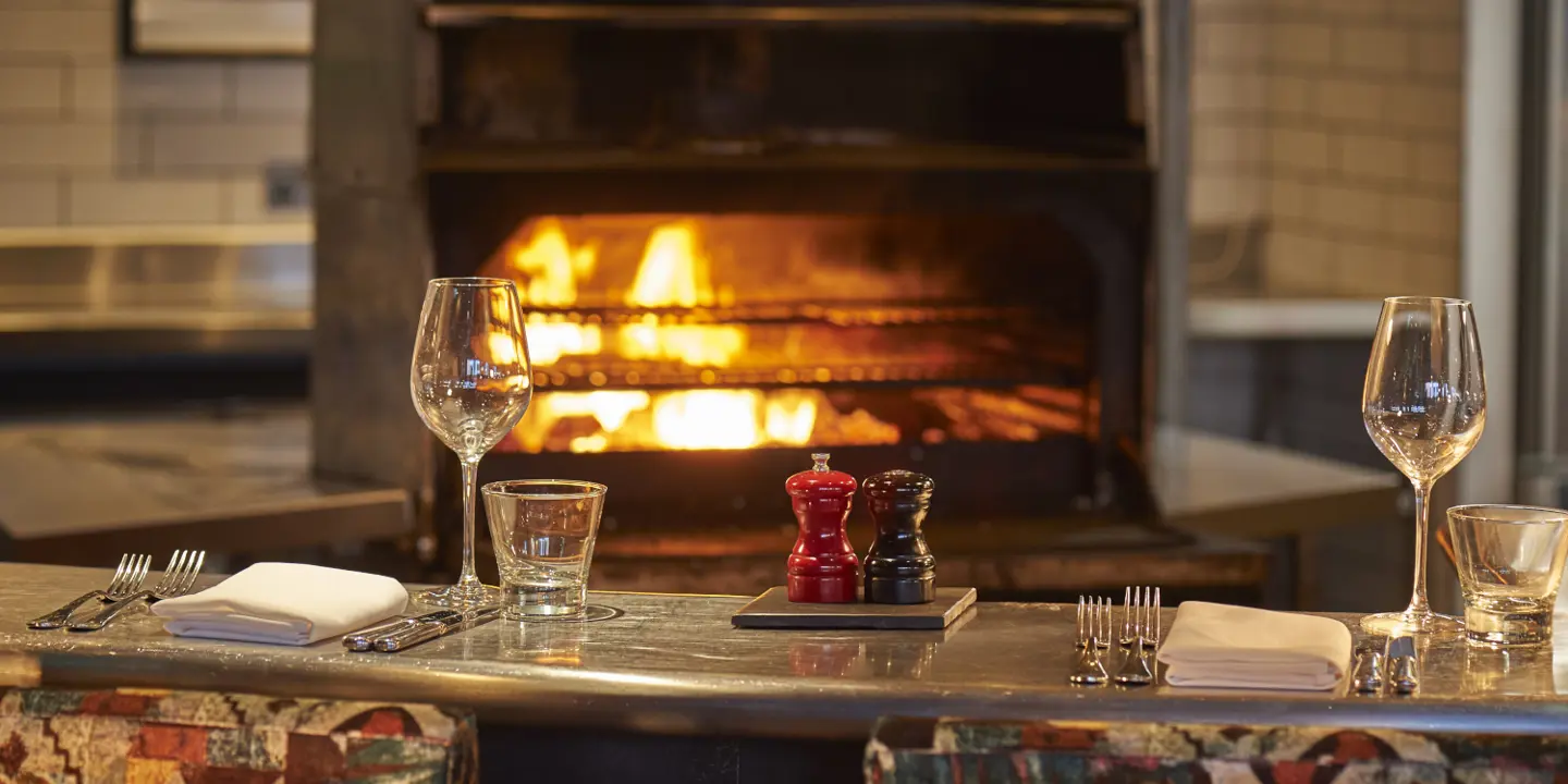 A table adorned with wine glasses, set against the backdrop of a cozy fireplace.