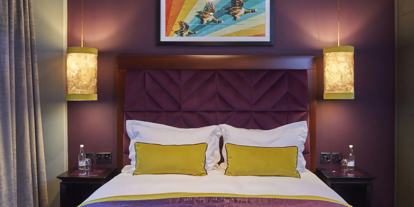 A bed featuring a purple headboard and adorned with yellow pillows.