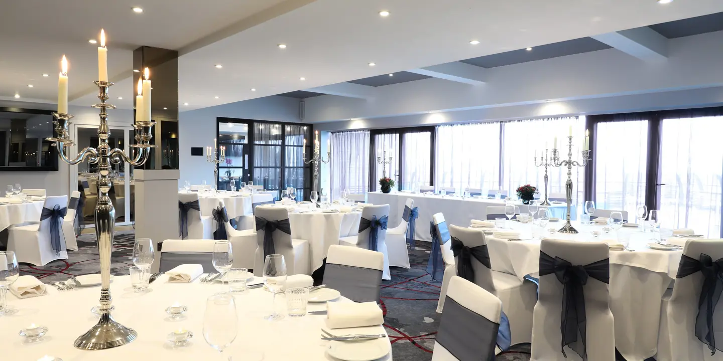 An elegantly arranged banquet room with pristine white tables and chairs.