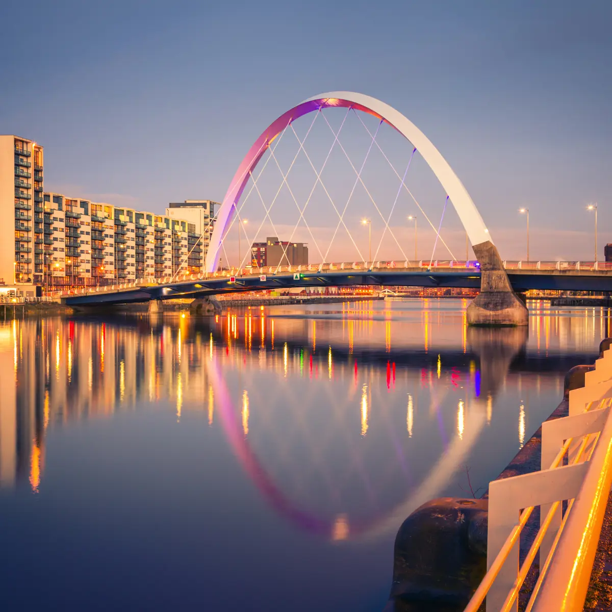 A bridge spanning a body of water alongside towering buildings.