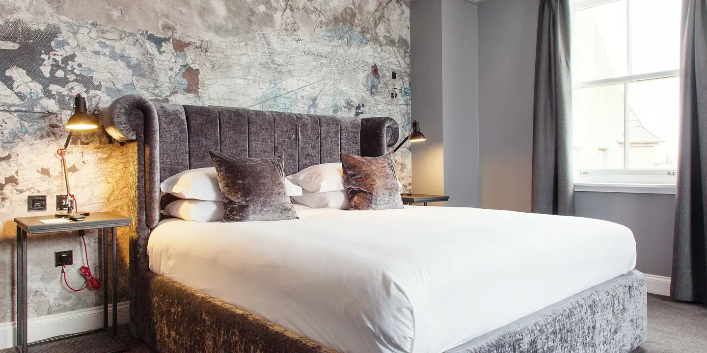 Bedroom featuring a grey velvet bed with silver bedside tables.