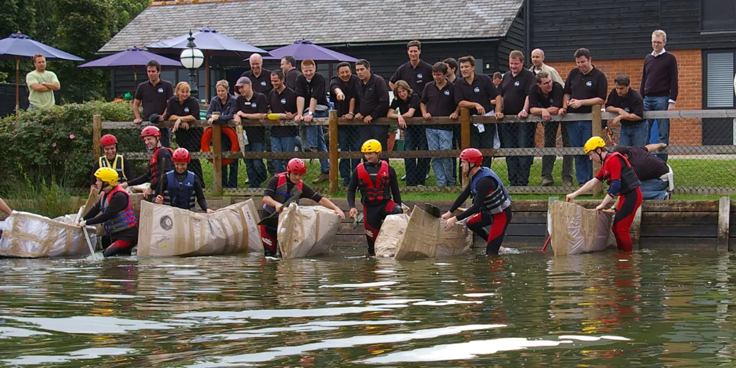 A group of individuals on cardboard boats a river.