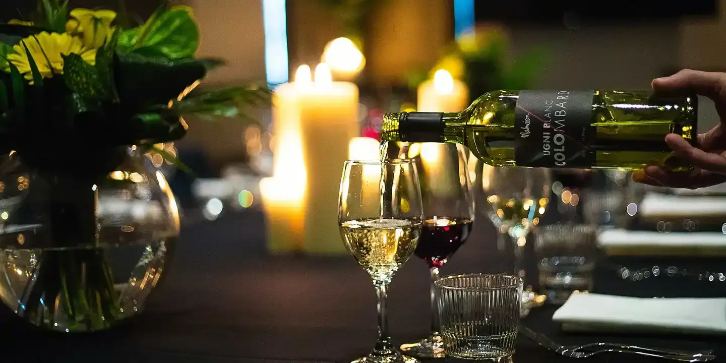 A person pouring wine into a glass.