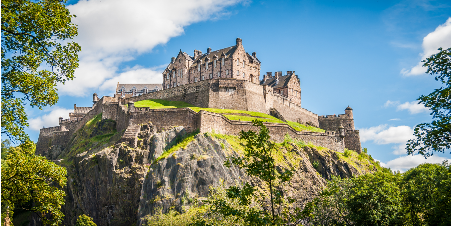 A castle atop a mountain, enveloped by lush trees.