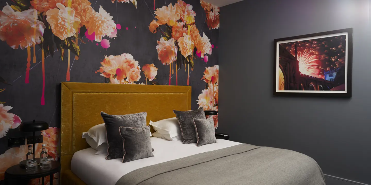 Bedroom featuring a comfortable bed and floral wallpaper behind the headboard.