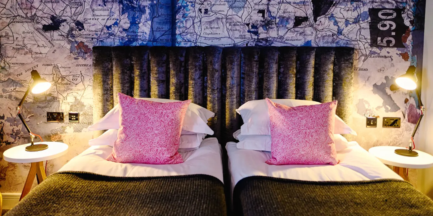 Two beds placed side by side with pink pillows.