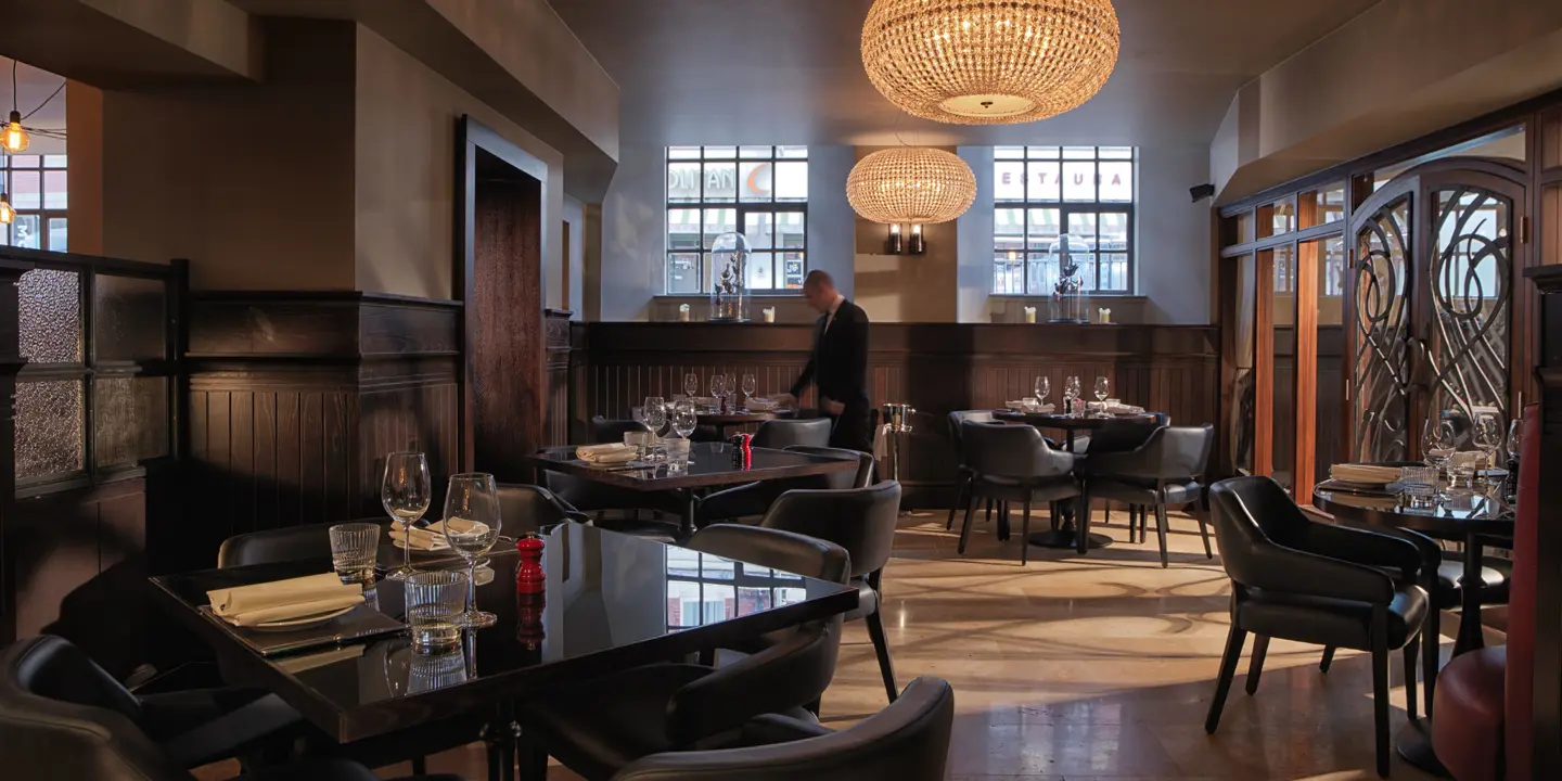 A restaurant featuring elegantly arranged tables, chairs, and exquisite chandeliers.