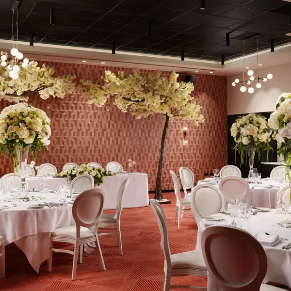 An elegantly decorated banquet room featuring pristine white tables and chairs.
