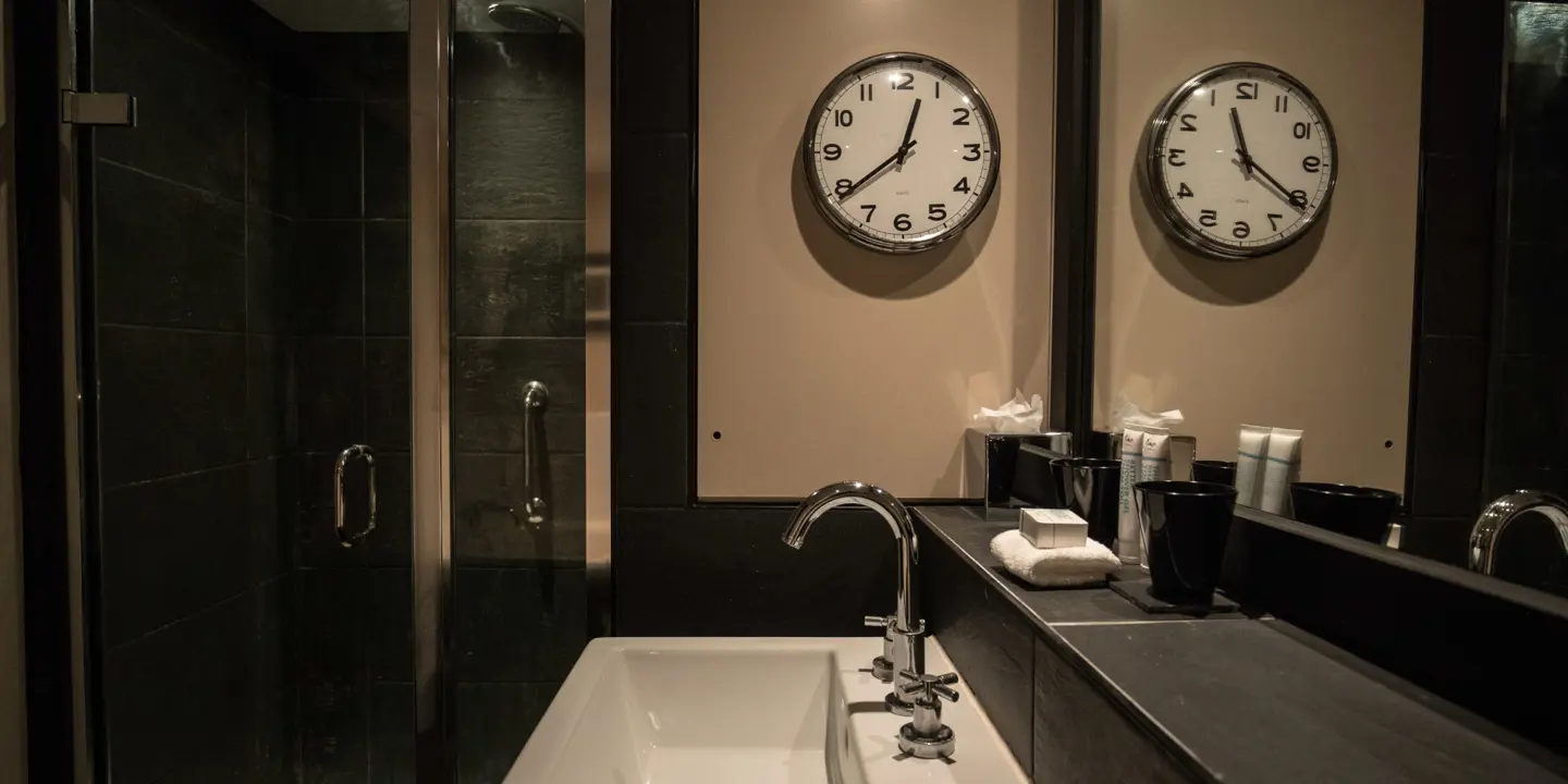 Bathroom featuring a wall clock, sink and shower.