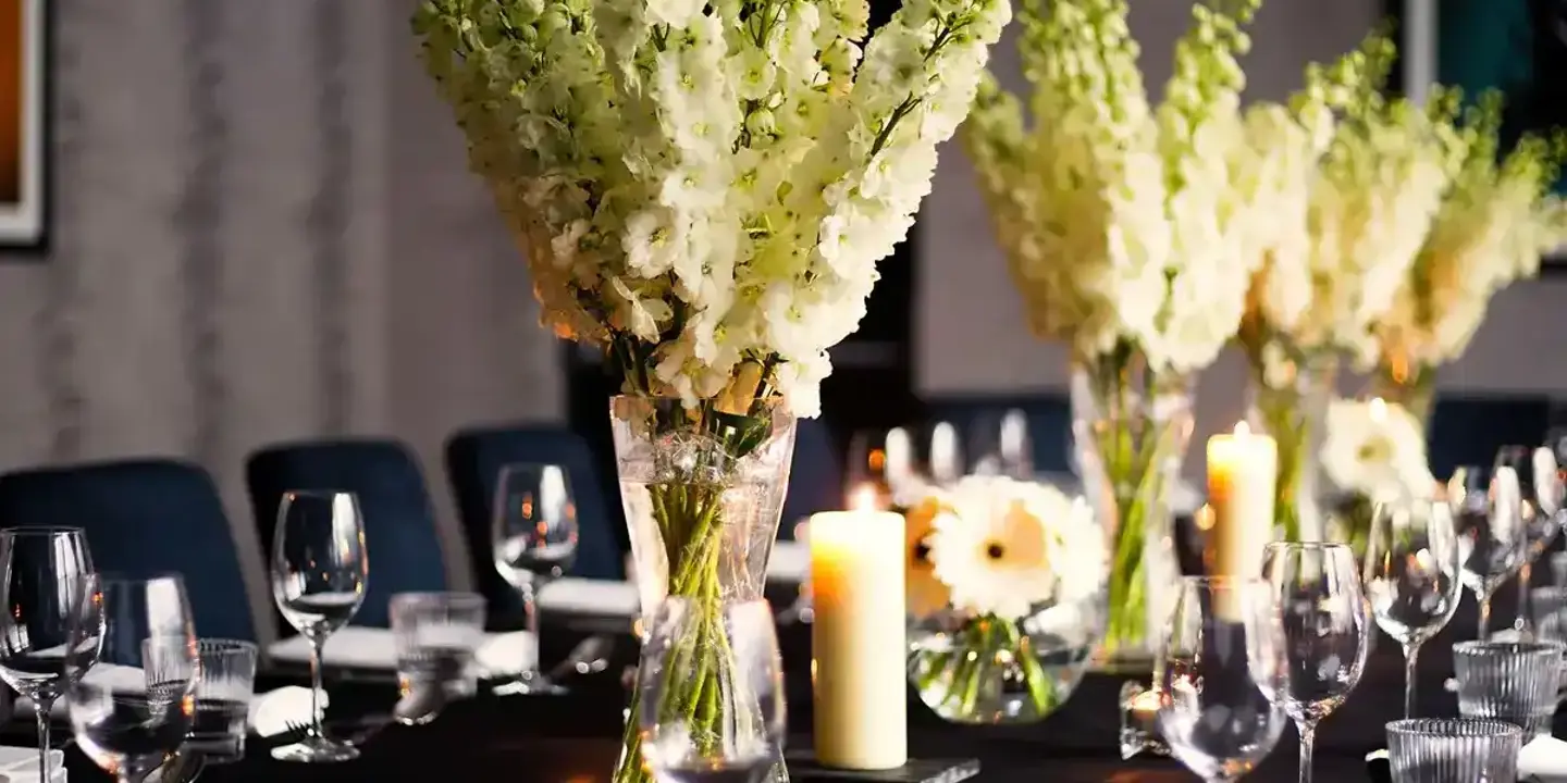 A beautifully arranged table for a formal dinner adorned with elegant candles and exquisite flowers.