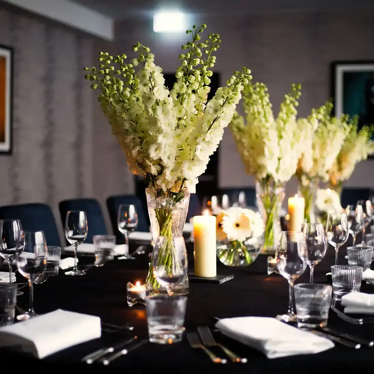 A beautifully arranged table for a formal dinner adorned with elegant candles and exquisite flowers.