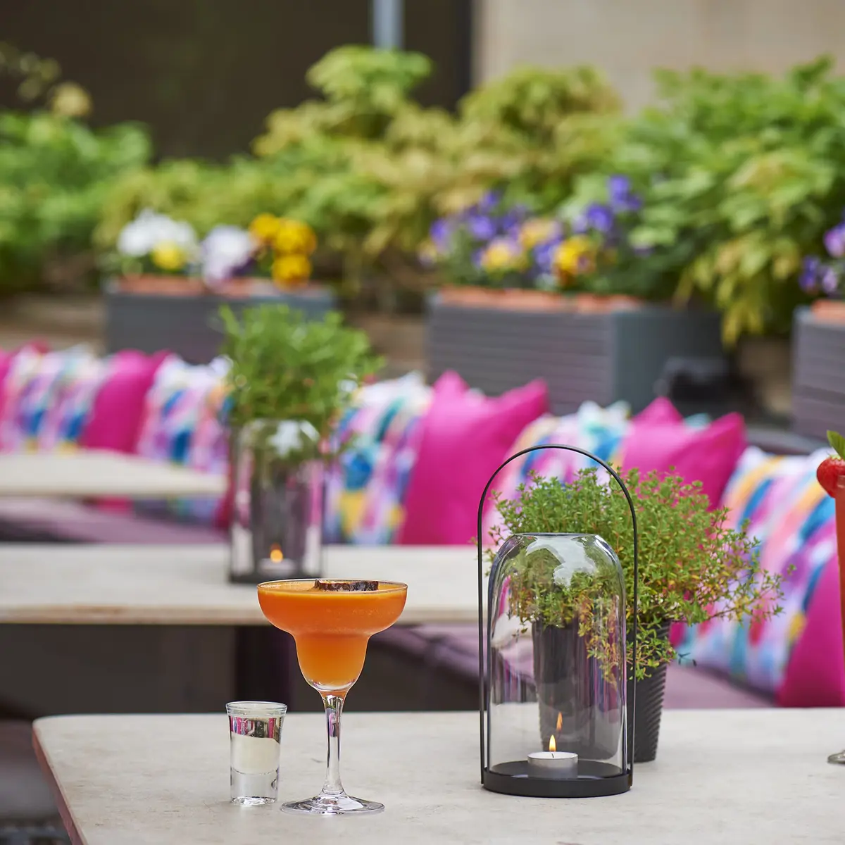 A vibrant outdoor seating area with 2 cocktails on a table