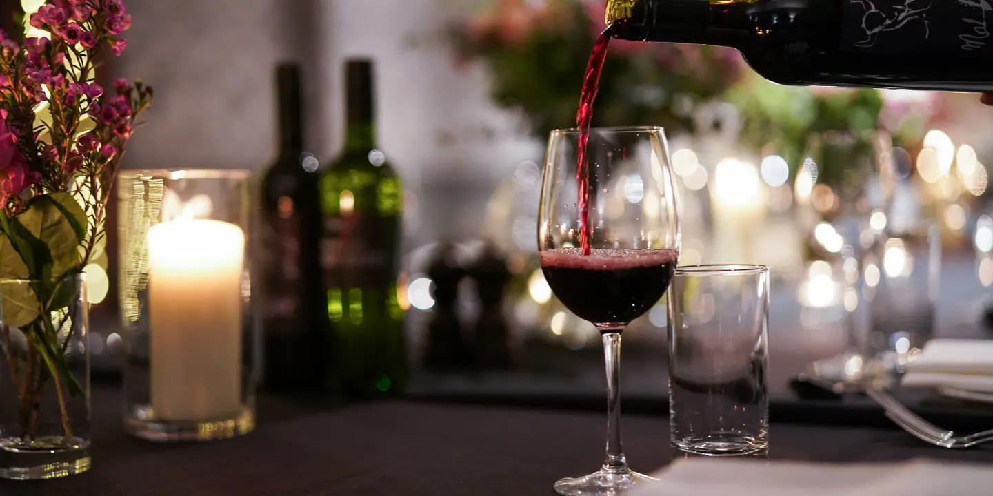 A glass of red wine being poured into a wine glass.