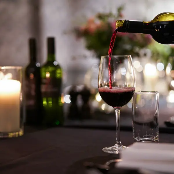 A glass of red wine being poured into a wine glass.