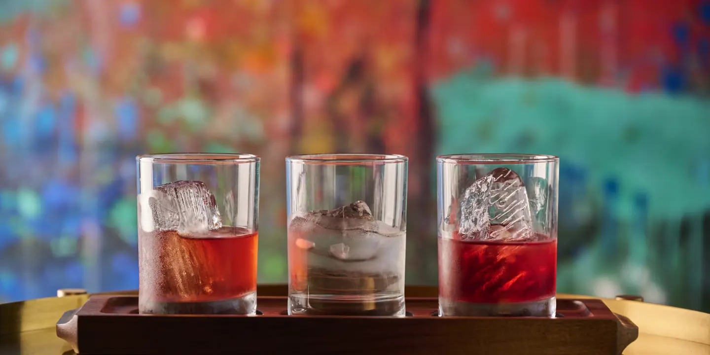 A person pouring a shot into two cocktail glasses.