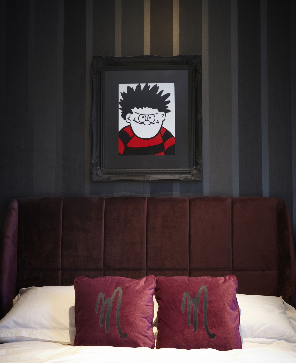 An elegantly made bed adorned with two plump pillows and a framed picture hanging on the wall.