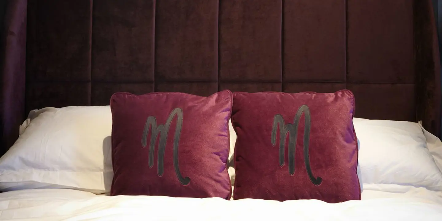 An elegantly made bed adorned with two plump pillows and a framed picture hanging on the wall.