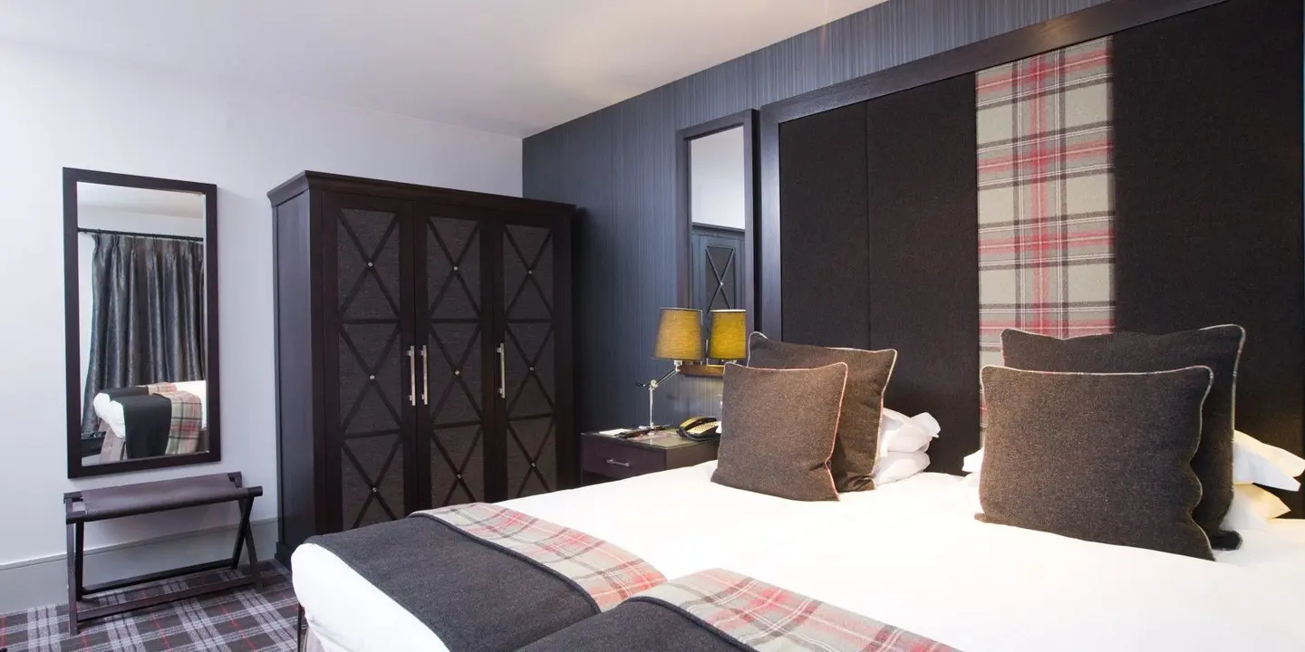 Two beds pushed together with a tartan headboard.