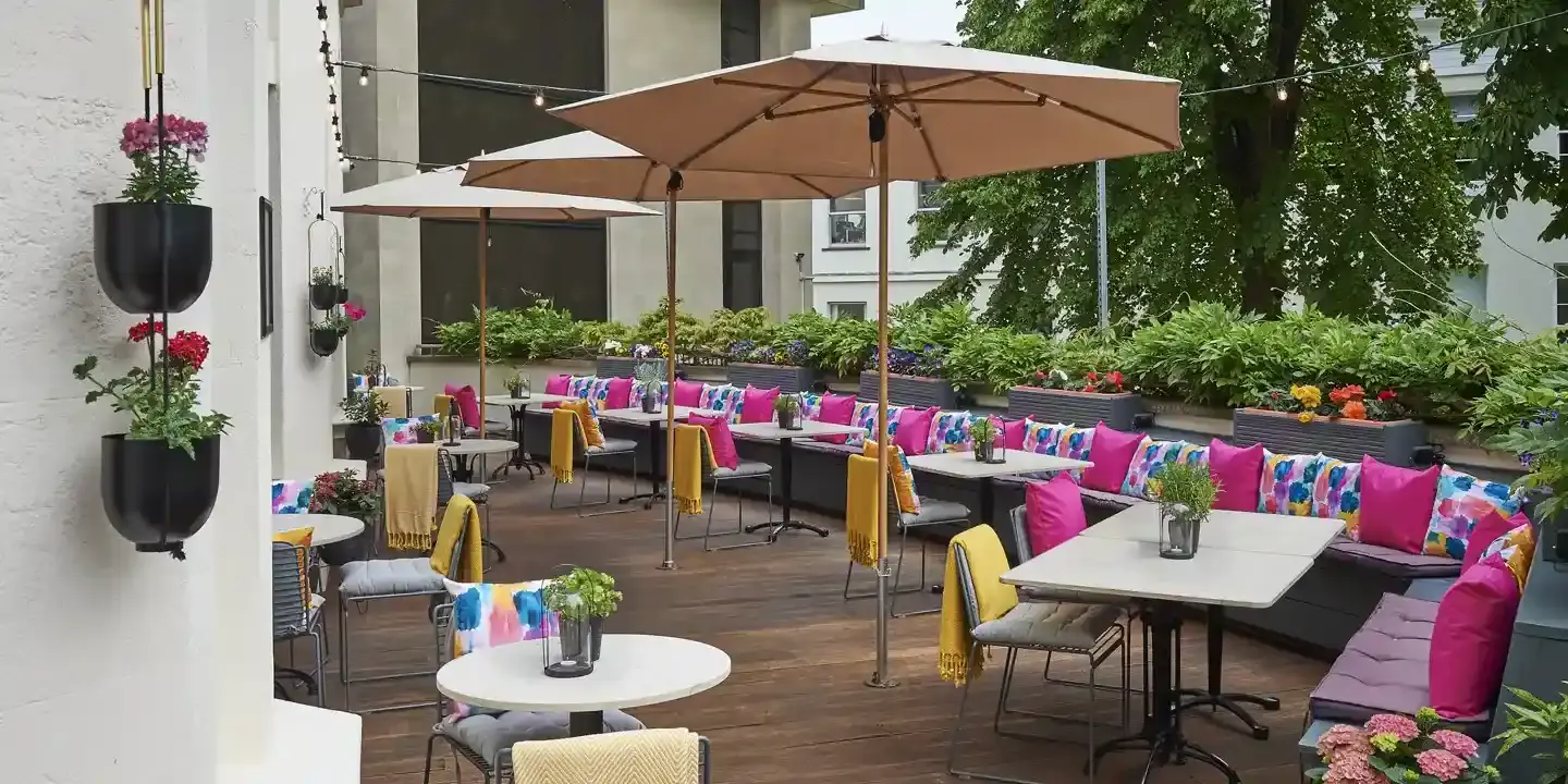 A patio featuring tables, colourful chairs, and umbrellas.