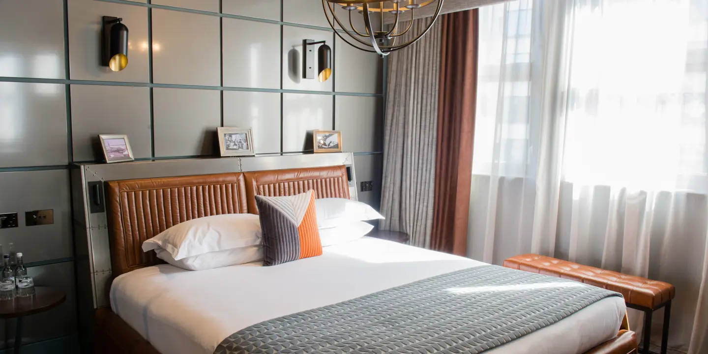 Spacious bedroom featuring a grand bed and an elegant chandelier.