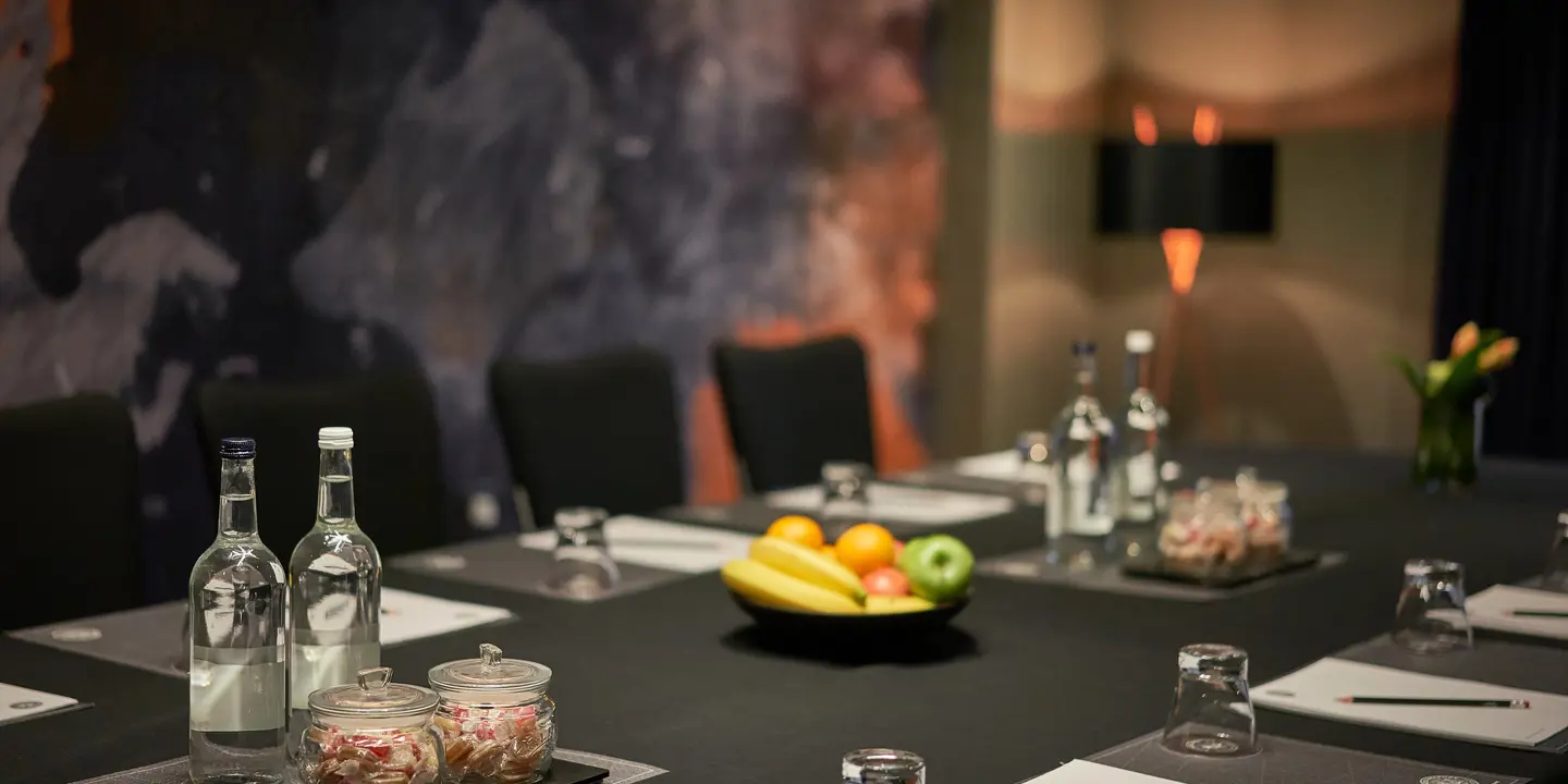 A table displaying a bowl of fresh fruit and bottles of water.