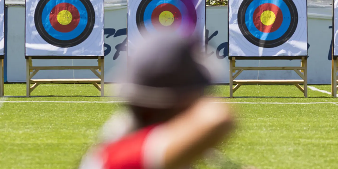 Someone holding a bow in front of archery targets.
