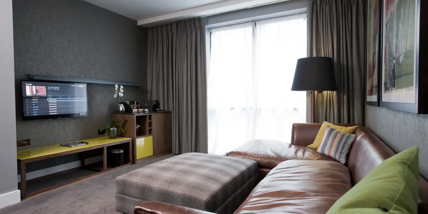 A well-furnished room featuring a flat-screen TV and brown leather sofa.