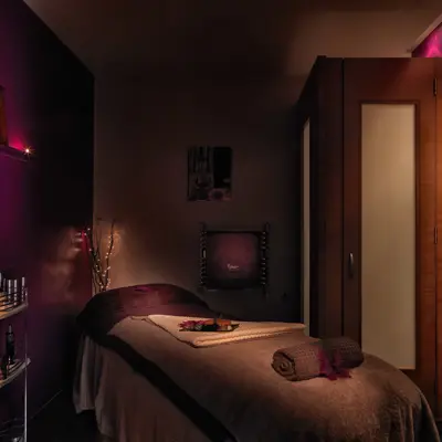 Spa Birmingham set up with massage bed with towels, and shelves neatly stocked with massage oils