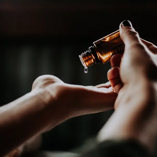 An individual using a bottle of oil on their hands.