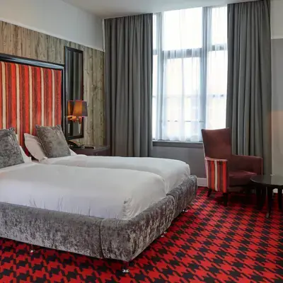 An image of a hotel room featuring two beds and a chair.
