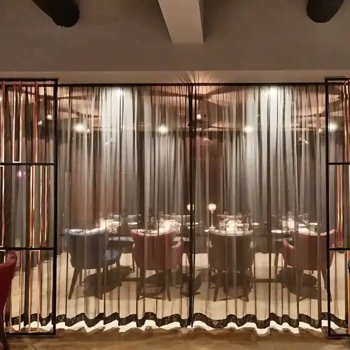A restaurant featuring a spacious room adorned with black tables and fabric chairs.