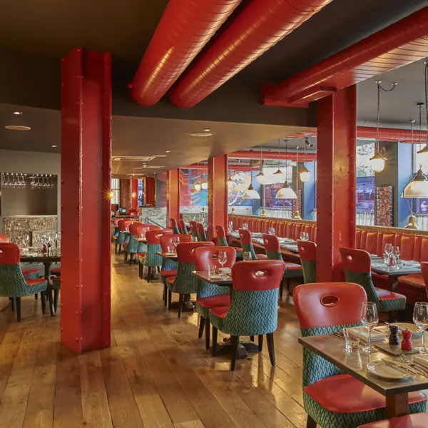 An eatery featuring vibrant red walls and stylish green chairs.