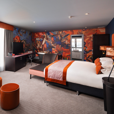 Bedroom featuring a comfortable bed, sofa, desk and bath tub.