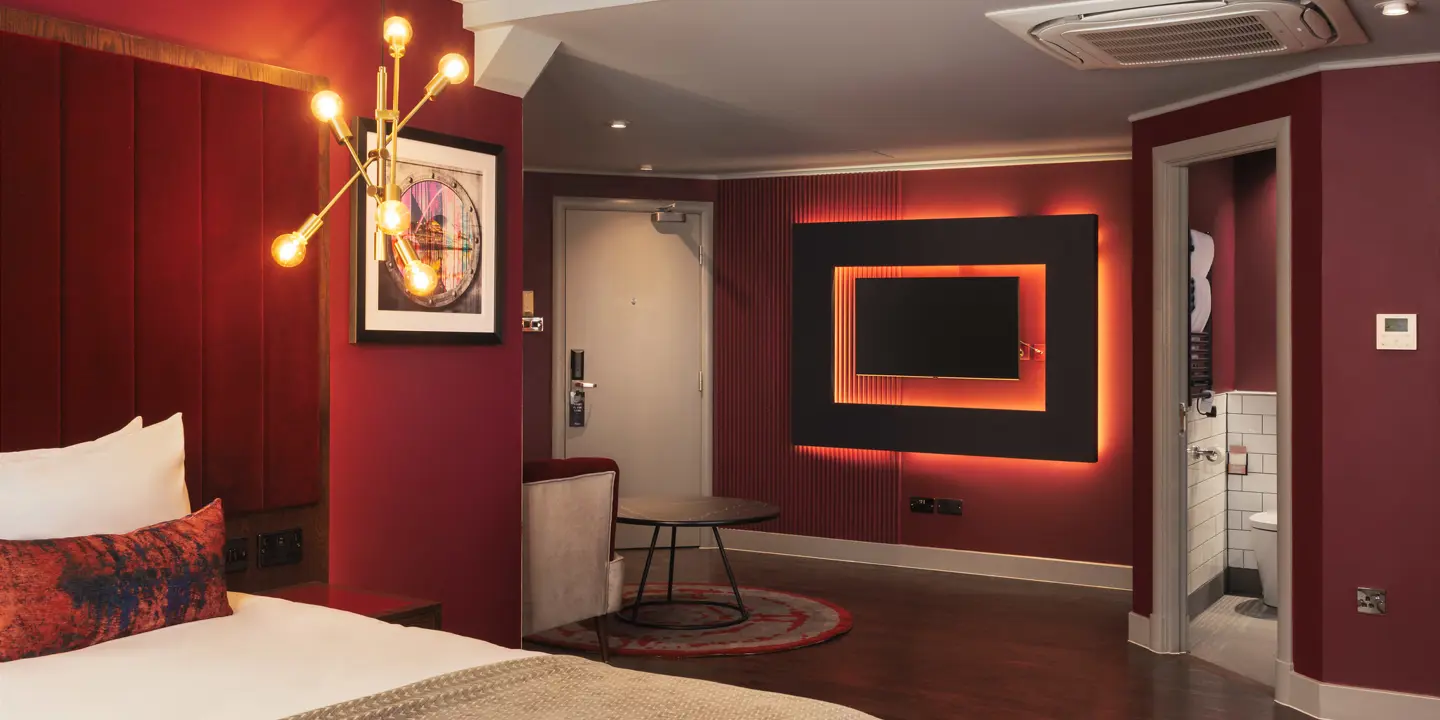 Spacious room featuring a comfy bed, mounted wall TV, seated area and separate bathroom