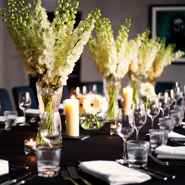 Table elegantly set for a formal dinner, adorned with candles and flowers.