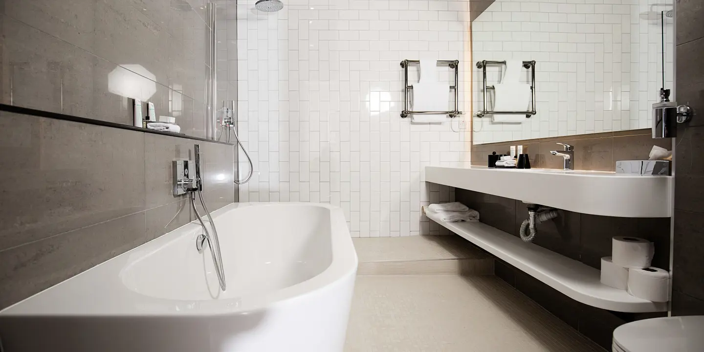 White bathtub positioned alongside a white toilet.