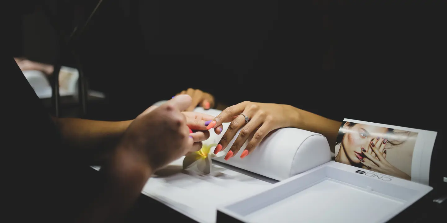 Spa Birmingham woman receives a manicure. Orange nail polish is applied to her nails