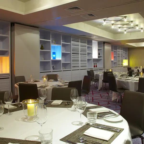 A dining room featuring multiple round tables elegantly decorated with brown chairs.