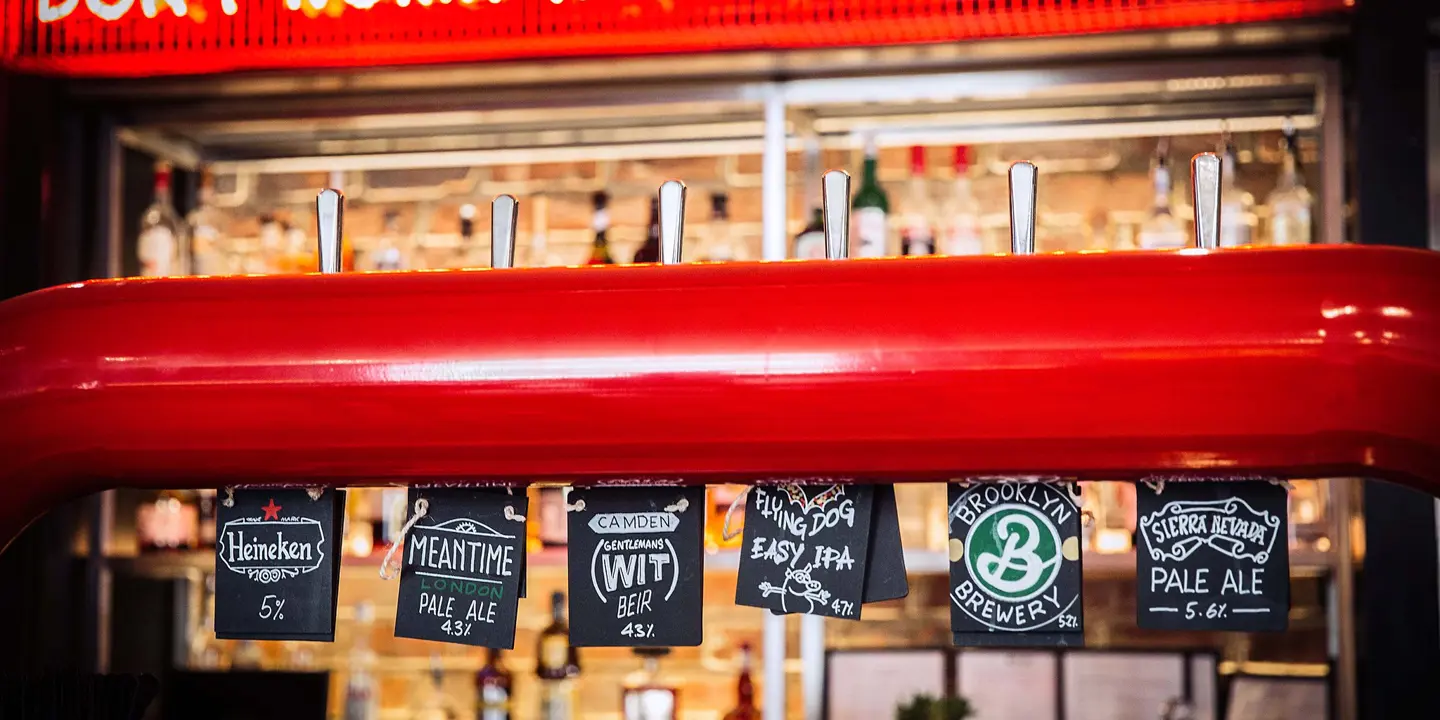 Row of beer taps displayed in front of a bar.