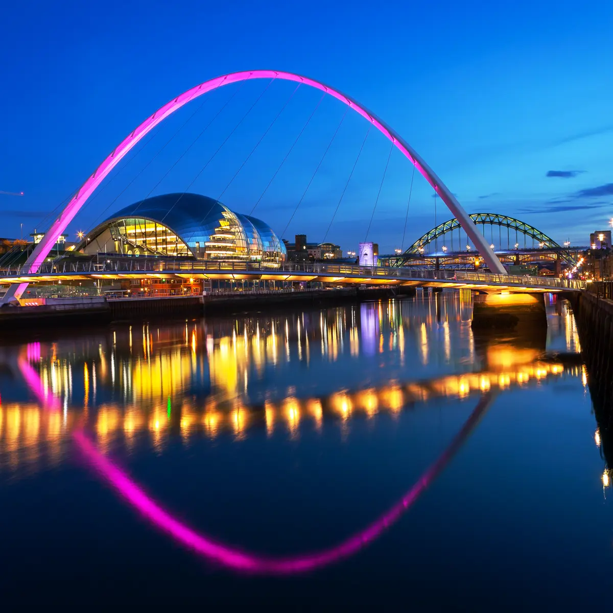 Nighttime view of a bridge spanning over a serene body of water.