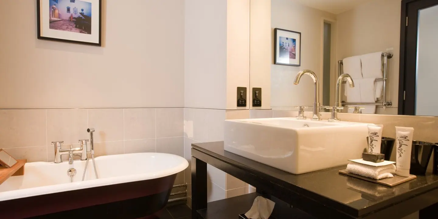 A bathroom featuring a bathtub, sink, and mirror.