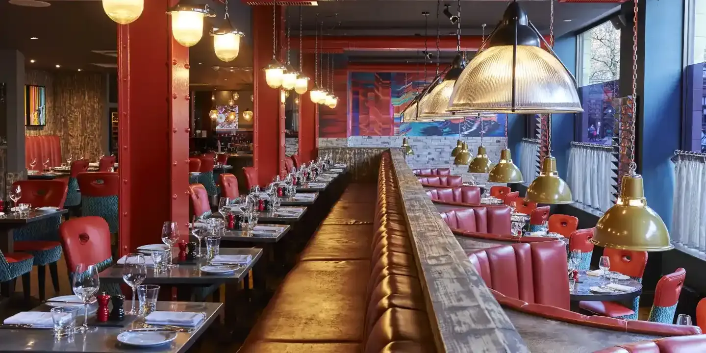 An image of a restaurant featuring a lengthy table adorned with red chairs.