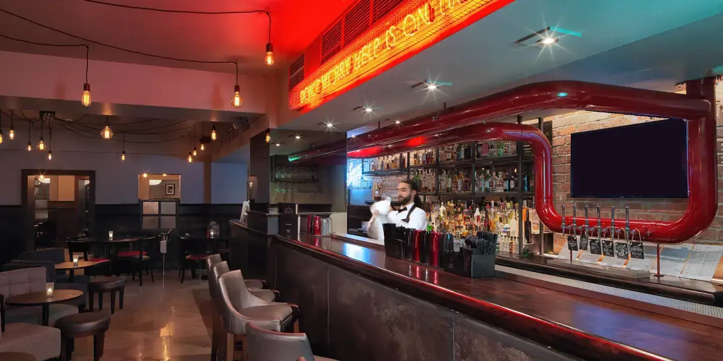 Man standing behind a bar counter in a pub.