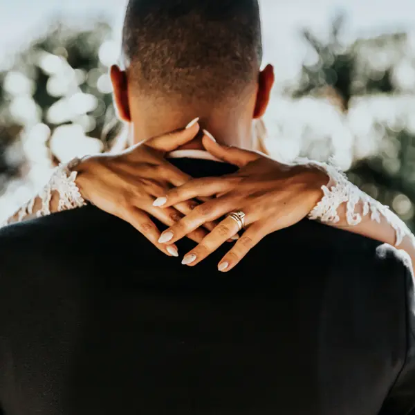 Close-up of a person hands resting on someones shoulders wearing a wedding ring.