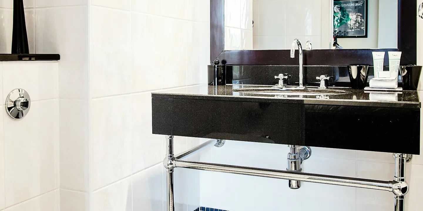 Black marble sink in a black and white tiled bathroom.